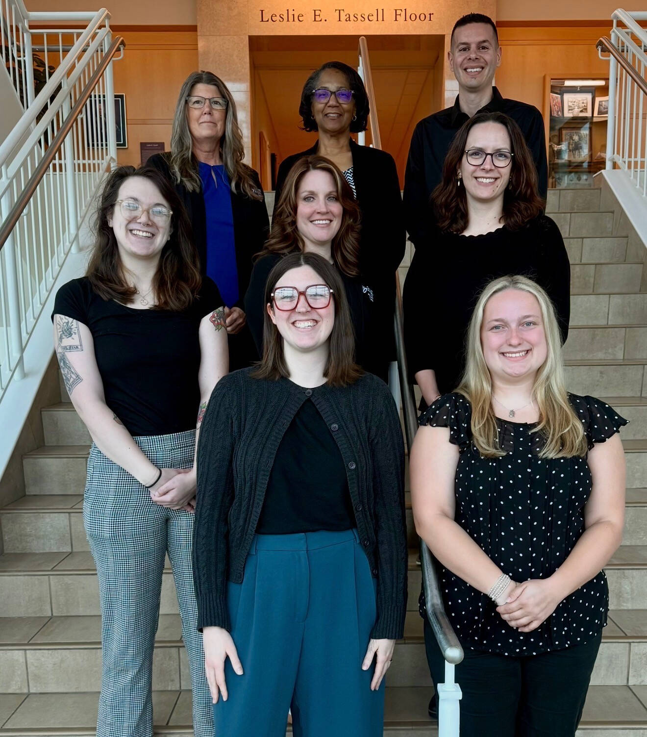 The team stands on the stairs smiling at the camera